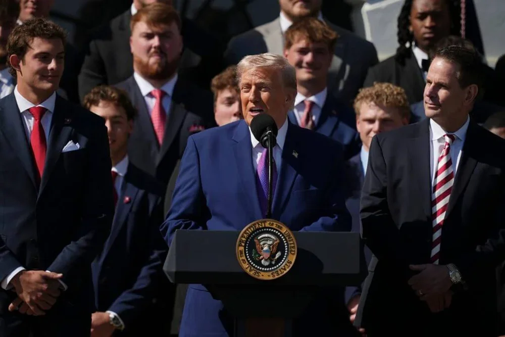President Donald Trump speaks as Charlie Becker, left, coach Curt Cignetti and members of the 2026 College Football Playoff national champions Indiana University look on during an event welcoming the team, Monday, May 11, 2026, on the South Lawn of the White House in Washington.